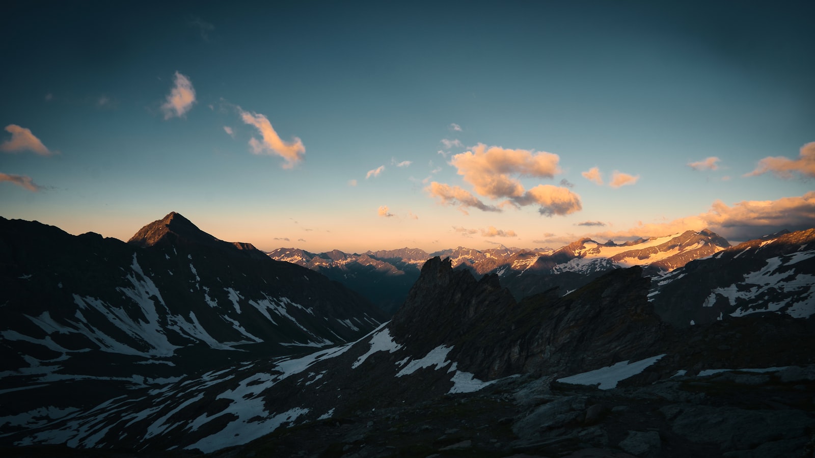 Golden light breaking over a vast alpine mountain range
